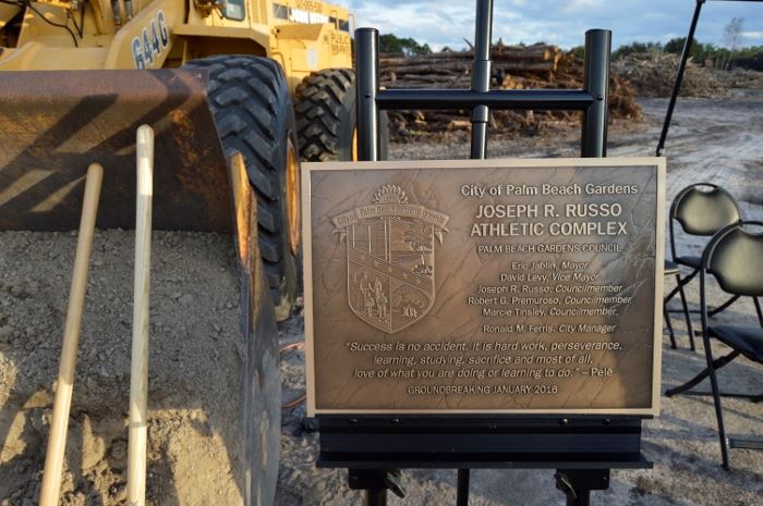 A plaque on an easel next to a tractor with dirt and shovels